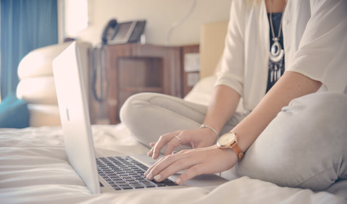 ベッドの上でブログを書いている女性