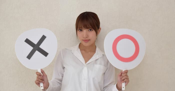 丸とバツのプラカードを持った女性